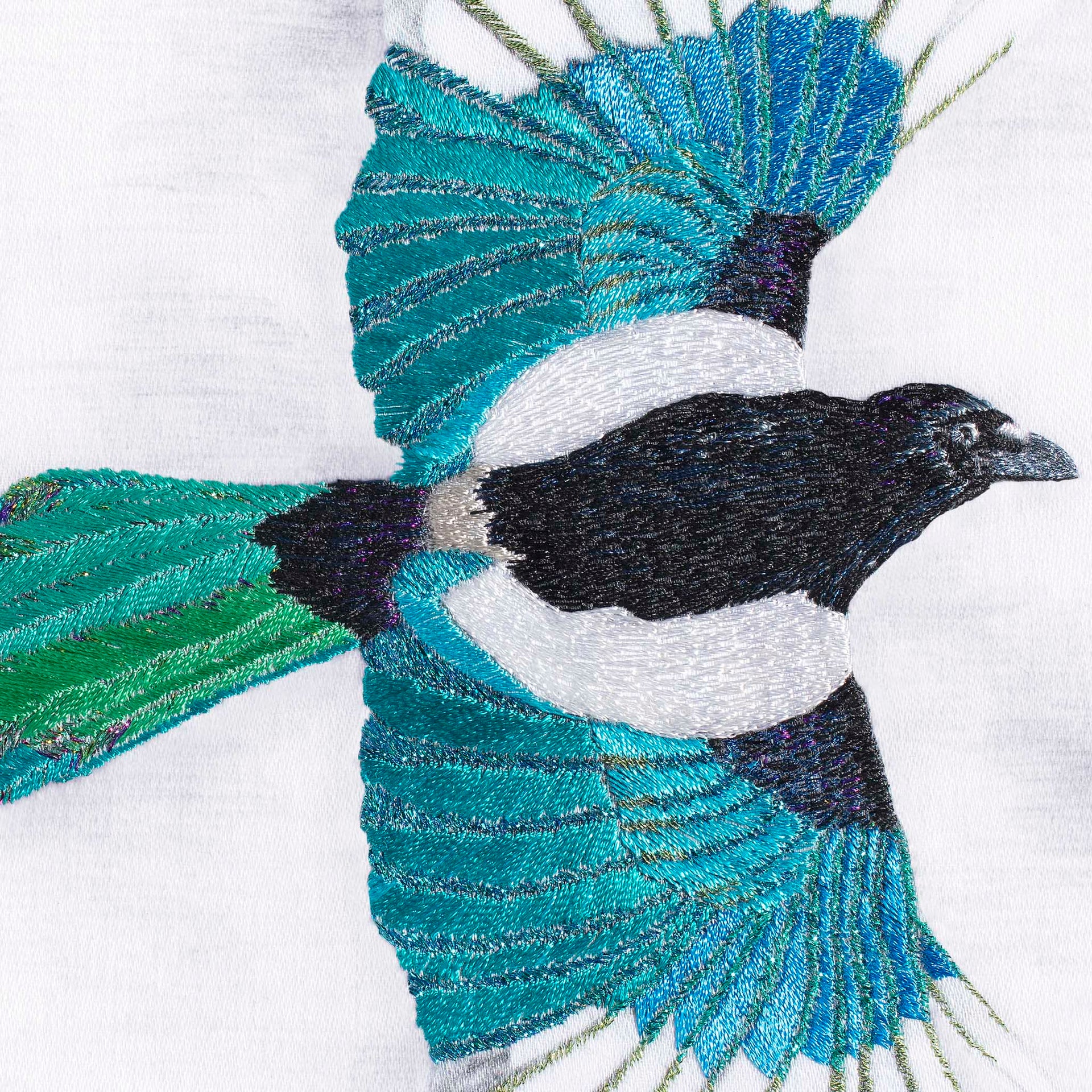 Magpie hand embroidered wall art close up.