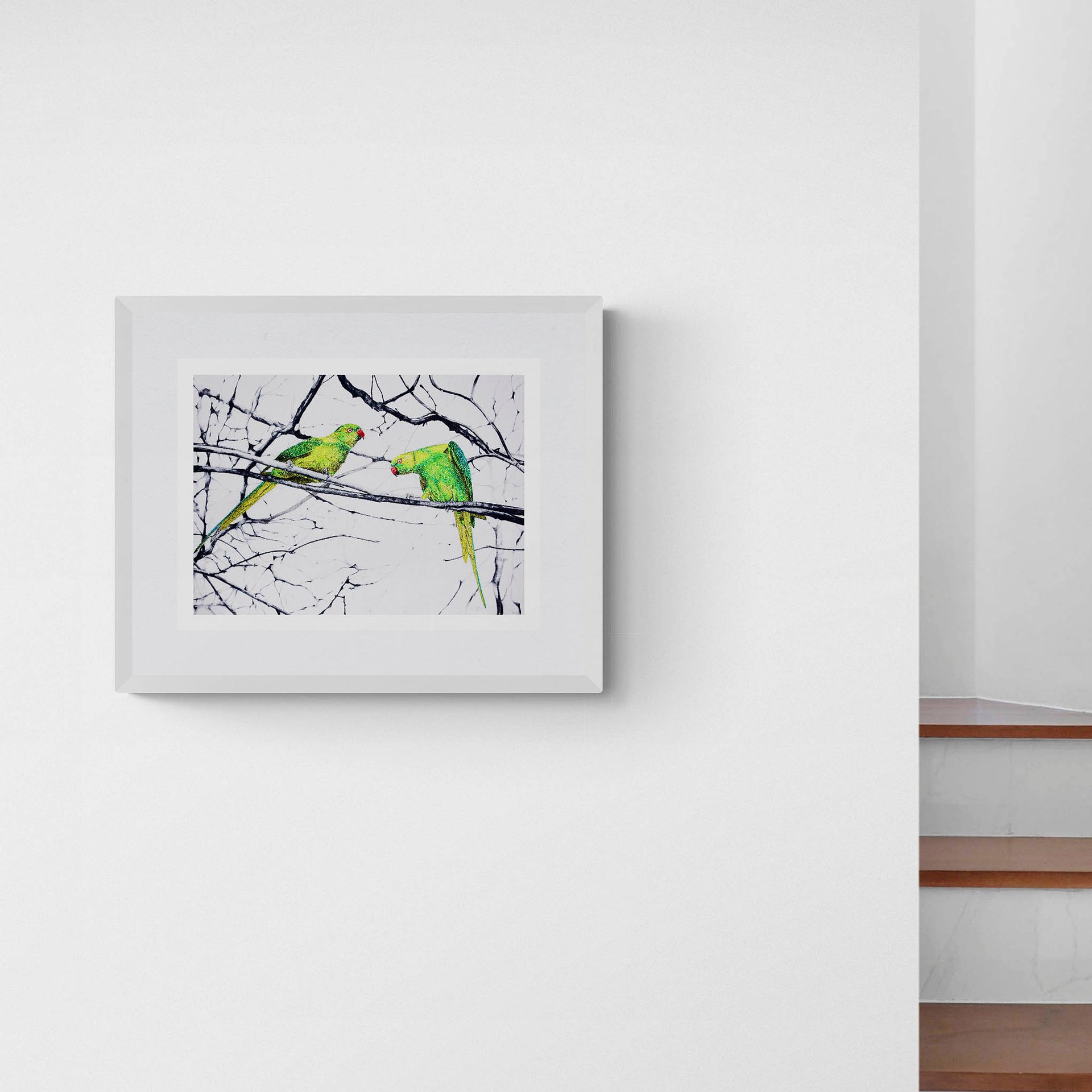 Hyde Park Parakeets limited edition embroidery art print by Susannah Weiland, shown in a white frame with white mount hung on a white wall next to a staircase, demonstrating the print's impact in a clean contemporary interior.