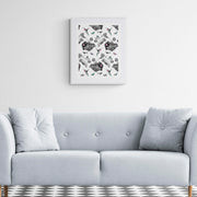 Luxury embroidered artwork by Susannah Weiland in a white frame displayed above a grey button-back sofa in a classic interior with a monochrome diamond-tiled floor. The Pink Hummingbird Limited Edition Wildlife Art Embroidery Print.