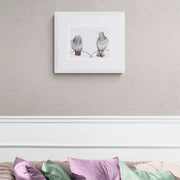 Contemporary textile art print of Regent's Park pigeons by Susannah Weiland, shown in a white frame on a cream wall above a sofa with coloured cushions — limited edition of 50.