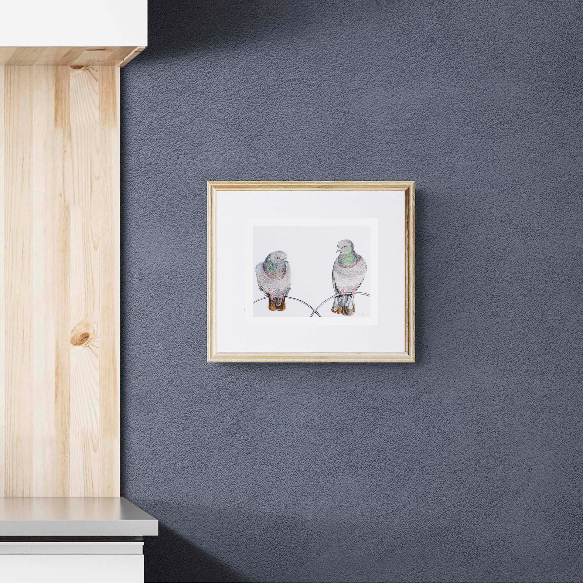Regent Pigeons luxury embroidered artwork print by Susannah Weiland displayed in a natural pine frame against a dark charcoal textured wall in a contemporary interior.