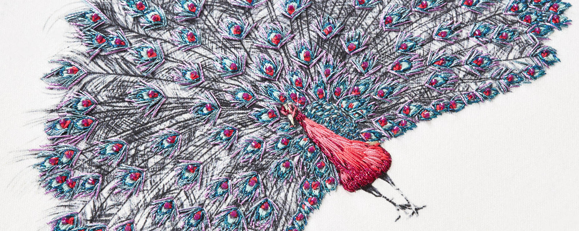 Pink peacock hand embroidered artwork close up