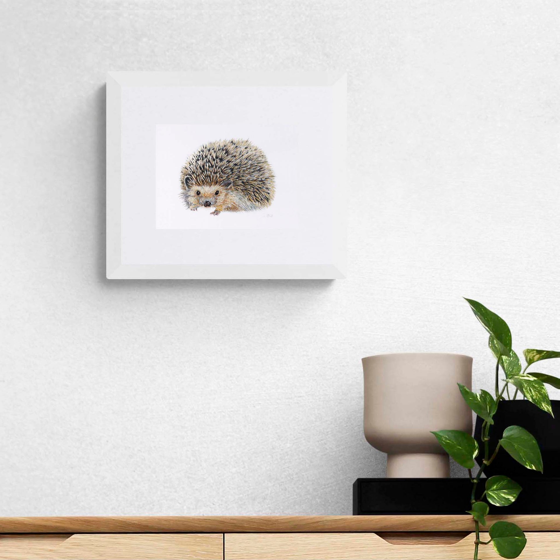 Hand embroidered hedgehog limited edition print in white frame on the wall