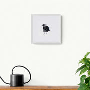 Limited edition print of hand embroidered bird with beads and sequins in white frame on the wall